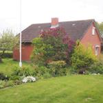 Rotes Backsteinhaus mit Gartenterrasse und blühenden Pflanzen.