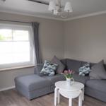 Ein Wohnzimmer mit grauem Sofa, weißem Tisch und Fenster mit Jalousie.