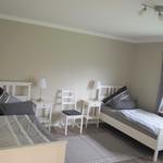 Zwei Einzelbetten, Nachttische, Stuhl und Fenster mit Vorhang.