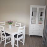 Essbereich mit weißem Tisch, vier Stühlen und Sideboard.