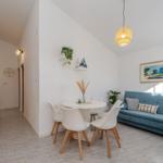 Dining area with table and chairs next to blue sofa and kitchen area.