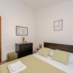 Bedroom with bed, nightstands, and dresser. Door leads to adjacent room.