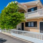 Two-story house with balcony, white railing, and large windows with black shutters.