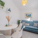 Living and dining area with blue sofa, white table and chairs, and wall shelves.