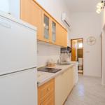 Kitchen with refrigerator, sink, and range hood. Toilet area is visible.