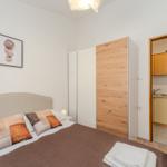 Bedroom with bed, wardrobe, and view into the kitchen.