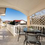 Terrace with table and chairs, view of buildings and sky.