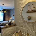 Waschbecken mit goldenem Wasserhahn und Spiegel an der Wand.