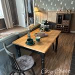 Essbereich mit Holztisch, Stühlen und dekorativer Wandtapete mit Hirschmotiven.