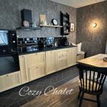 Küche mit Holzschränken, schwarzer Arbeitsplatte und Essbereich mit Holztisch.