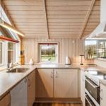 Küche mit Holzwand und -decke, Fenster, Arbeitsplatten und Geräten.