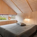 Schlafzimmer mit Holzwand und Dachfenster. Bett mit grauer Bettdecke.