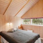 Schlafzimmer mit Holzwand, Bett, Stuhl und Fenster zum Garten.