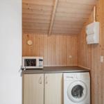 Küchenbereich mit Mikrowelle, Waschmaschine und Holzwand.