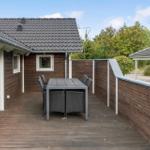 Terrasse mit Tisch und Stühlen, Holzwand und Gartenhaus im Hintergrund.