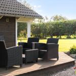 Terrasse mit Sitzgruppe, Grill und Blick auf grünen Rasen.