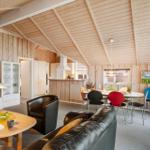 Wohn- und Essbereich mit Holzwand, Sofa, Tisch und Stühlen.