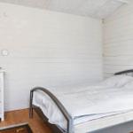 Schlafzimmer mit Bett, Schrank und Wandlampe. Holzboden und weiße Wände.