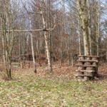 Holzspielplatz im Wald mit Schaukel und Klettergerüst.