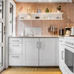 Küche mit weißen Schränken, Holzwand und Küchenzeile