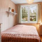 Schlafzimmer mit Holzwand, Bett und Fenster mit Blick auf Außenbereich.
