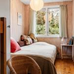 Ein Schlafzimmer mit Holzwand, Bett, Fenster und Stuhl.