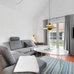 Living room with gray sofa, round table, and TV. Terrace via glass door.