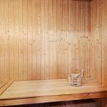 Sauna with wooden walls, bench, and wooden bucket.