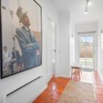 Hallway with red tiles, wall art, and glass door to the garden.