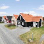 Row of wooden houses with red roofs and white window frames along a gravel road.