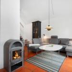 Living room with gray sofa, round table, and wood stove.