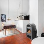 Dining area with table, chairs, and wood stove. Terracotta floor and white walls.