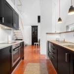 Kitchen with black cabinets, wooden countertop, and red tiles
