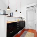 Kitchen with black cabinets, wooden countertop, and red tiles.