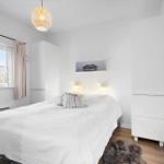 Bedroom with white bed, window and white wardrobes.