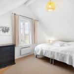 Bedroom with sloped ceiling, bed, dresser, and window.