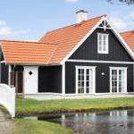 Black wooden house with red roof and white bridge over a canal.