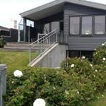 Moderne Villa mit Terrasse und Stufen zur Eingangstür.