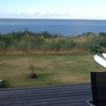 Terrasse mit Blick auf Meer, Grasfläche und zwei weiße Kajaks.