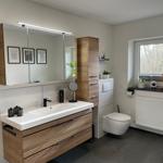 Badezimmer mit Waschbecken, Spiegel und Toilette. Fenster mit Pflanzen und Ankerdekoration.