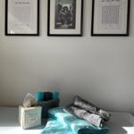 Drei gerahmte Bilder an der Wand über einem Waschbecken mit Handtüchern und Papiertüchern.