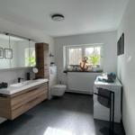 Bad mit Waschtisch, Spiegel und Fenster. Anker und Pflanzen auf Fensterbank.