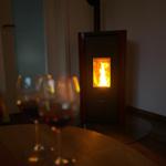 Im Wohnbereich brennt ein Kaminofen, vor ihm stehen zwei Weingläser auf einem Tisch.