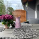 Terrasse mit Tisch, Stühlen und Blumenarrangement.