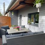 Terrasse mit Sitzgruppe, Tisch und Pflanzen an Hauswand.