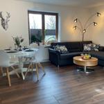 Wohn- und Essbereich mit Sofa, Tisch und Stühlen sowie Fenster und Beleuchtung.