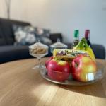 Auf dem Tisch stehen Äpfel, Bananen und Schokolade. Im Hintergrund ist ein Sofa.