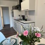 Esstisch mit Blumen und Kerzen, Küche im Hintergrund