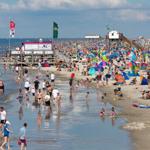 Viele Menschen genießen den Strand mit bunten Sonnenschirmen und Zelten.
