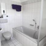 Badezimmer mit Badewanne, Dusche, WC und Heizung.